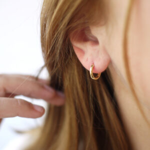 Mulher usando Argolinha mini redonda minimalista feita a mão em ouro 18k