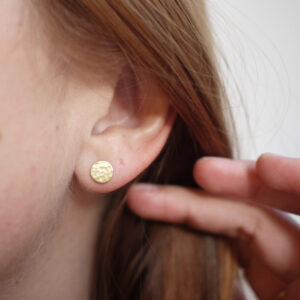 Mulher usando Brinco minimalista de. formato circular feito a mão com um disco de ouro 18k martelado