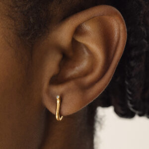 Mulher usando Brinco minimalista delicado feito a mão em ouro 18k em forma de V com diamante na ponta