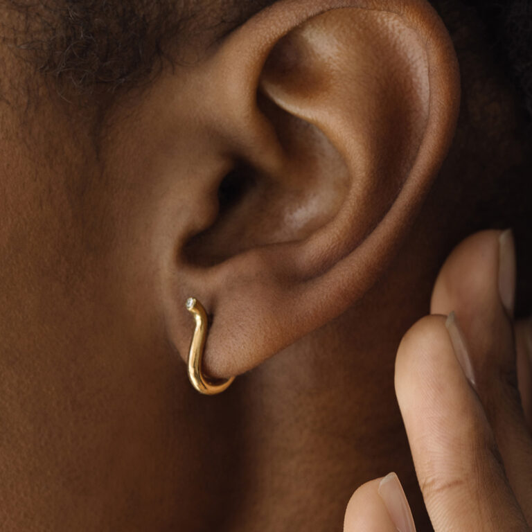 Mulher usando Brinco minimalista delicado feito a mão em ouro 18k em forma de V com diamante na ponta