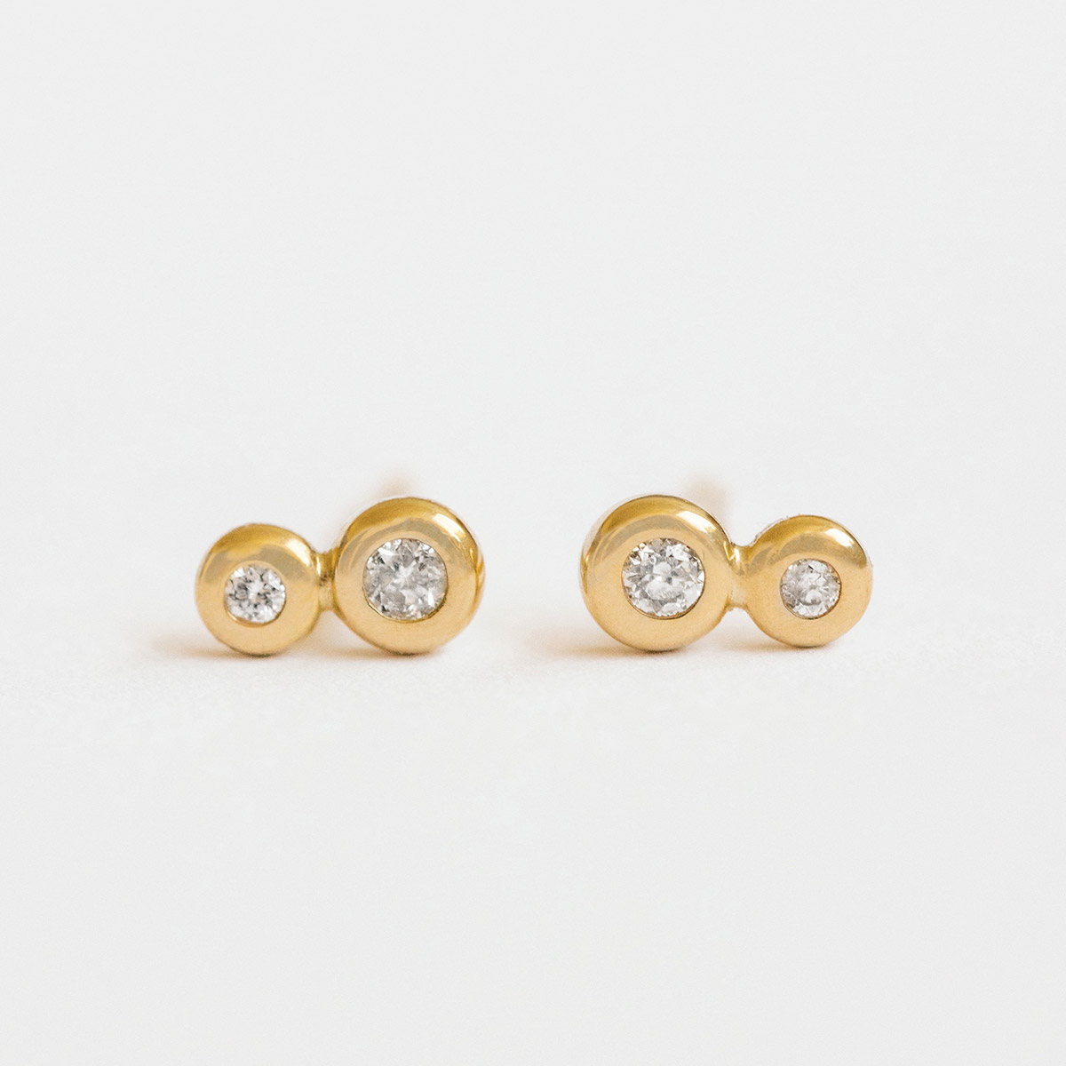 Brinco minimalista com um disco feito a mão de ouro 18k e um diamante no Brinco delicado minimalista feito a mão em ouro 18k com dois diamantes de diferentes tamanhos.