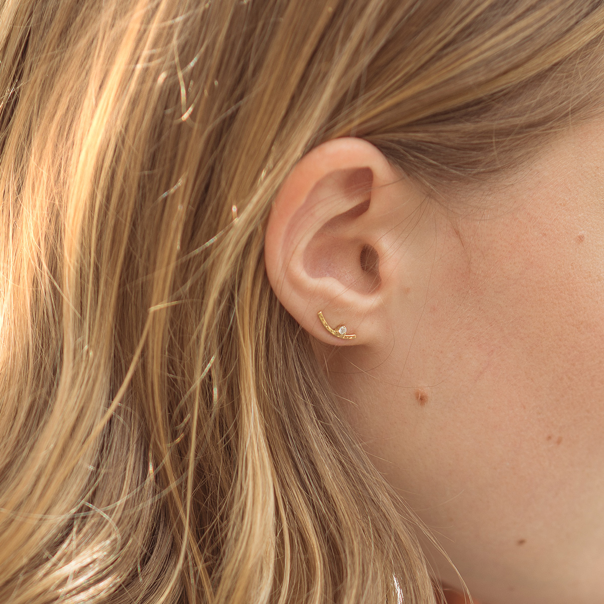 Mulher usando Brinco minimalista com diamantes feito a mão em ouro 18k martelado usado como ear cuff