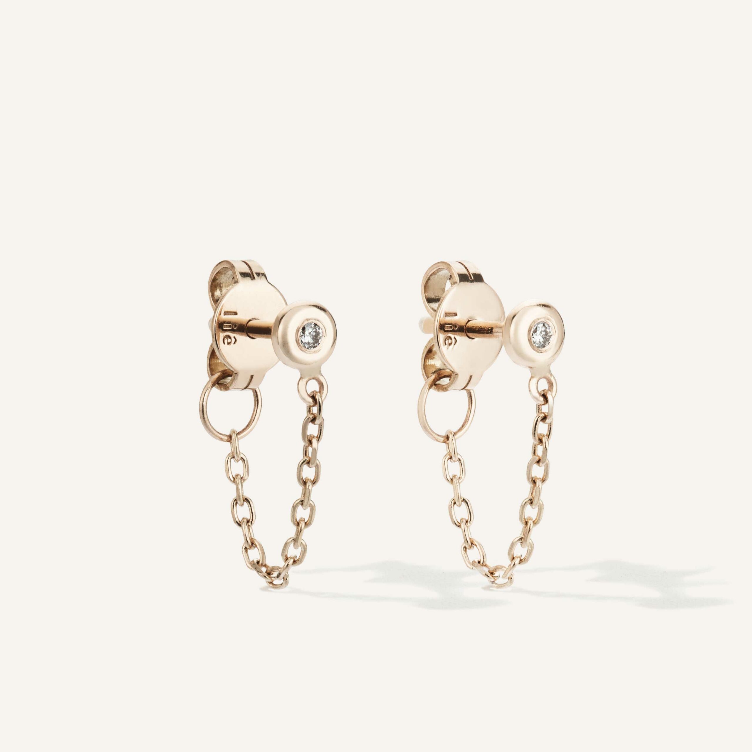 Brinco minimalista feito a mão em ouro 18k com diamante na ponta e corrente ligando a tarraxa