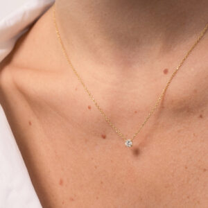 Mulher usando colar minimalista feito a mão em ouro 18k com diamante