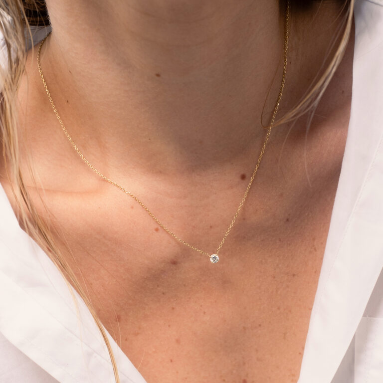 Mulher usando colar minimalista feito a mão em ouro 18k com diamante