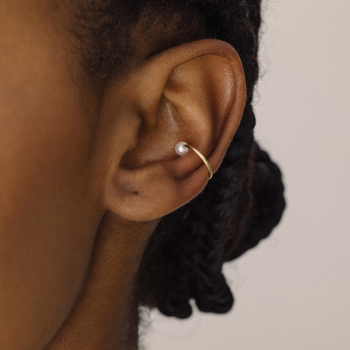 Mulher usando Ear cuff minimalista usada como piercing feita a mão em ouro 18k com pérola natural