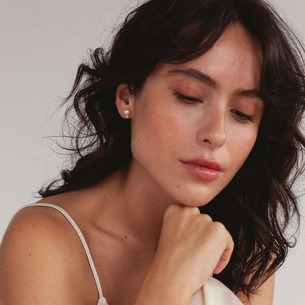 Mulher usando Brinco minimalista feito a mão em ouro 18k com duas pérolas naturais em tamanhos diferentes