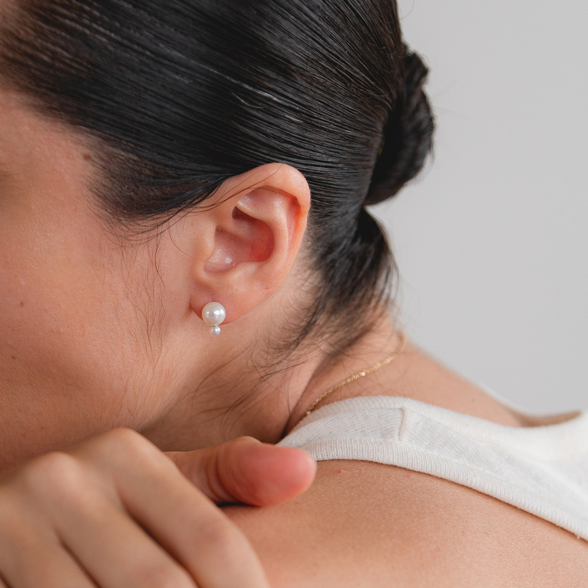 Mulher de coque usando Brinco minimalista feito a mão em ouro 18k com duas pérolas naturais em tamanhos diferentes