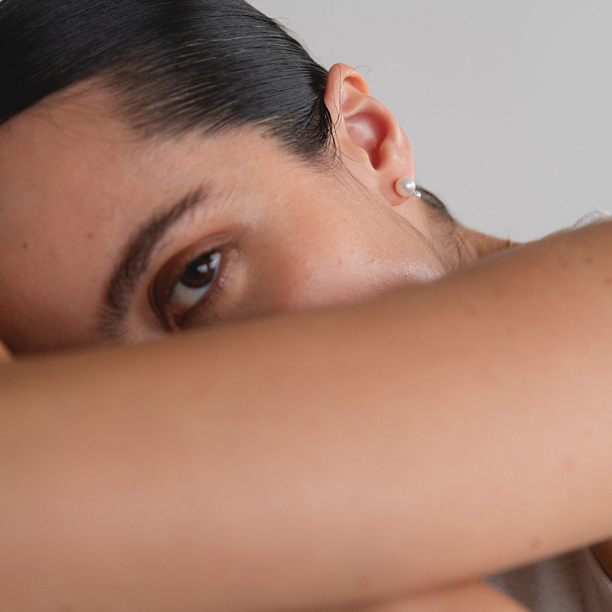 Mulher de coque usando Brinco minimalista feito a mão em ouro 18k com duas pérolas naturais em tamanhos diferentes