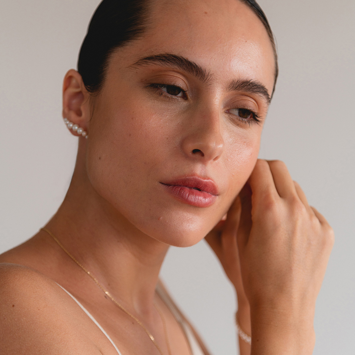 Mulher usando Pulseira, Colar e Brinco minimalistas feitos a mão em ouro 18k com sete pérolas naturais em tamanhos diferentes