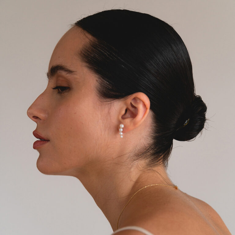 Mulher usando Brinco minimalista feito a mão em ouro 18k com quatro pérolas naturais em tamanhos diferentes