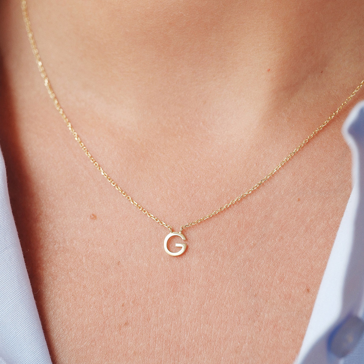 Mulher usando colar minimalista feito a mão em ouro 18k com letra da inicial do nome