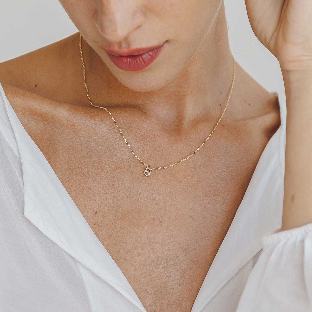 Mulher usando colar minimalista feito a mão em ouro 18k com letra da inicial do nome