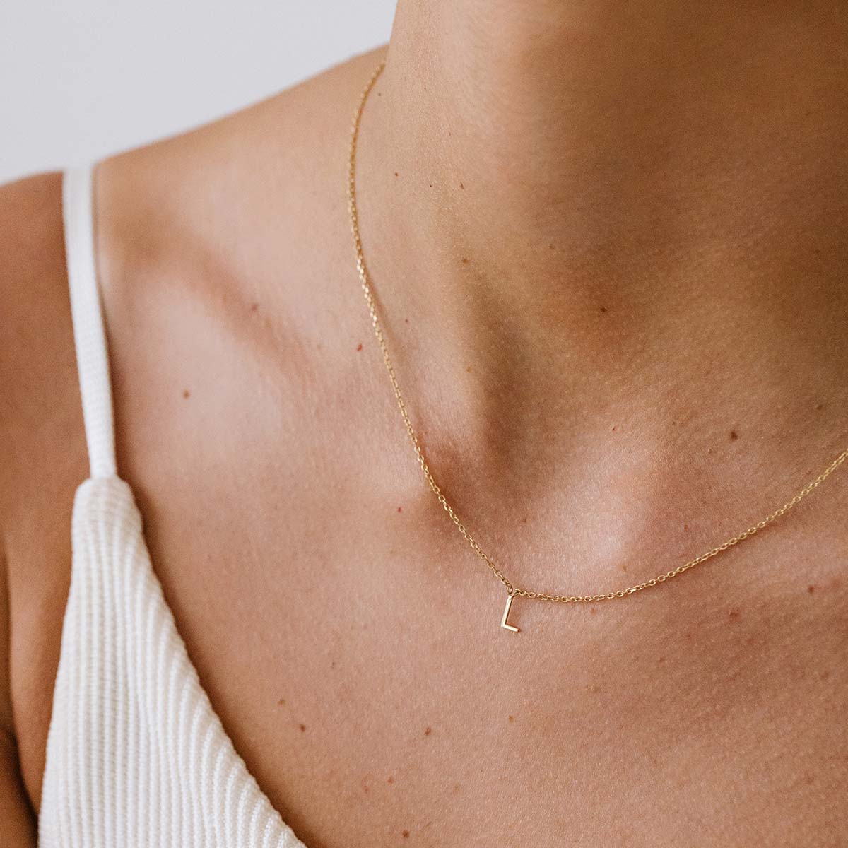 Mulher usando colar minimalista feito a mão em ouro 18k com letra da inicial do nome