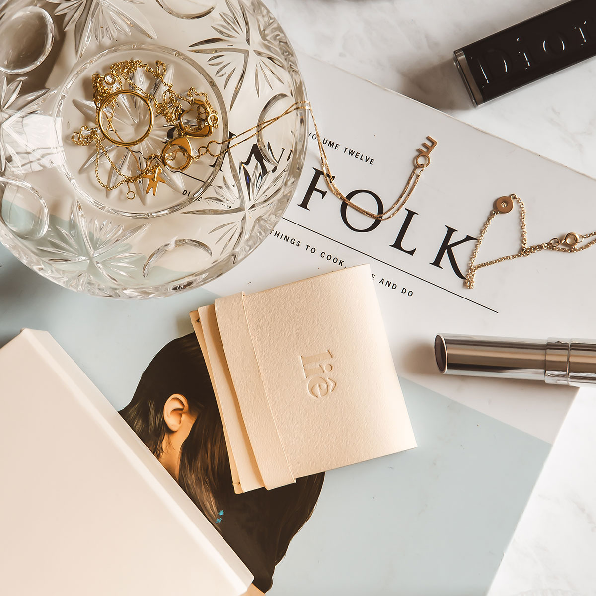 mesa com revista e joias como colar minimalista feito a mão em ouro 18k com letra da inicial do nome