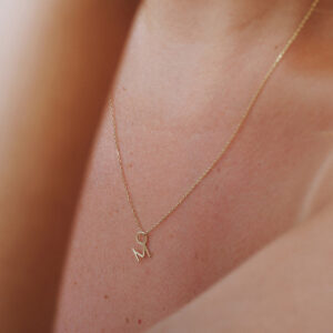 Mulher usando corrente com pingente minimalista feito a mão em ouro 18k com letra da inicial do nome