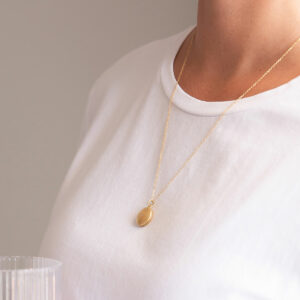 Mulher usando Corrente com pingente relicário em formato redondo minimalista feito a mão em ouro 18k com diamante no lado de fora e dois espaços para foto