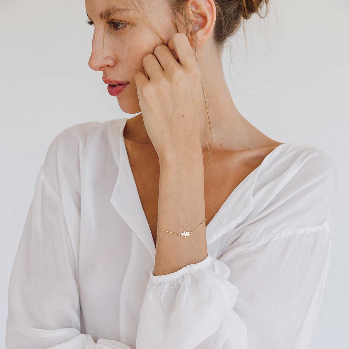 Mulher usando Pulseira minimalista representando filha feita a mão em ouro 18k com diamante e corrente cartier fina