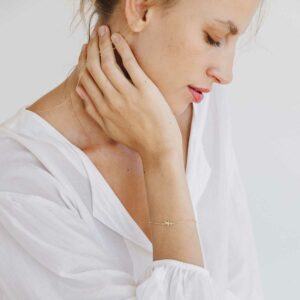Mulher usando Pulseira minimalista representando filho feita a mão em ouro 18k com diamante e corrente cartier fina