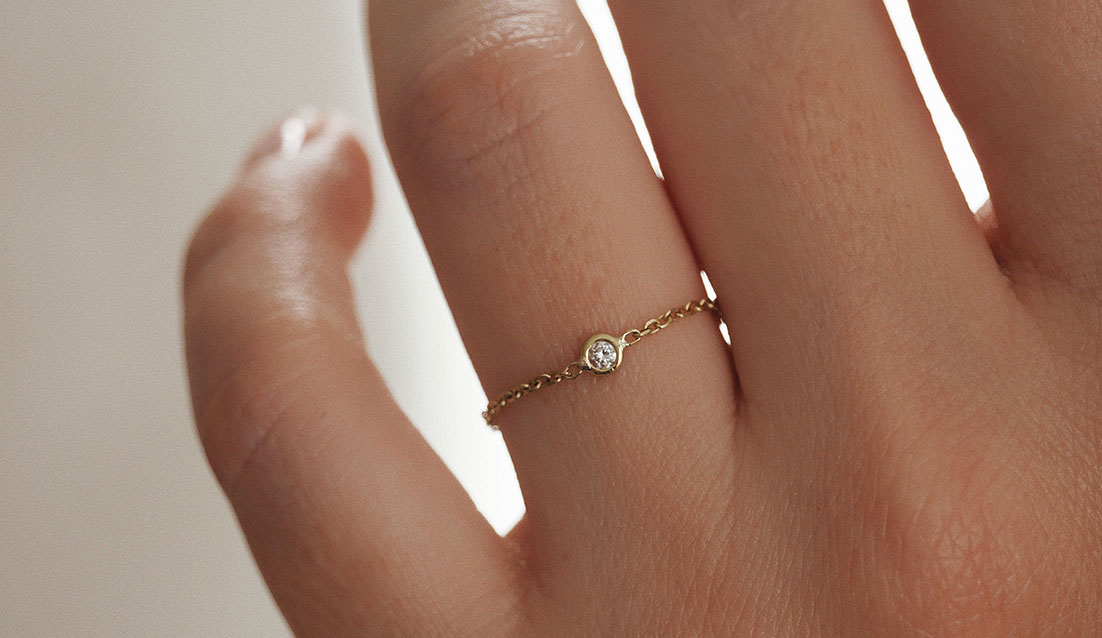 Anel de corrente em ouro 18k com diamante de 3 pontos sendo usado no dedo