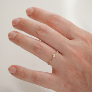 Anel de corrente em ouro 18k com diamante delicado usado no dedo em look minimalista