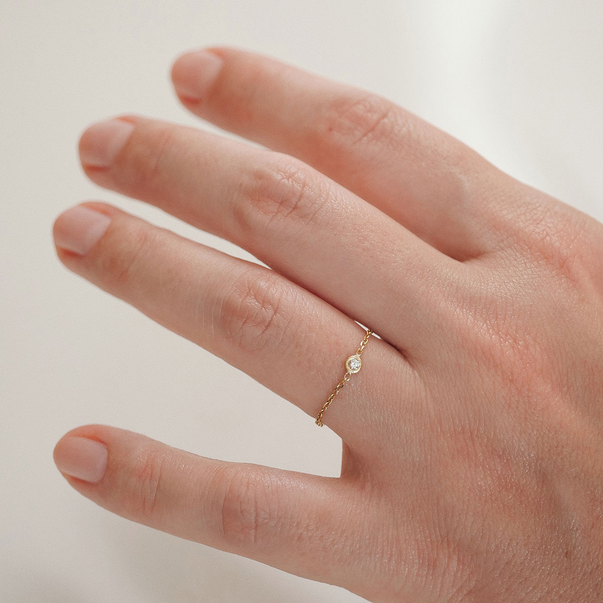Anel de corrente em ouro 18k com diamante delicado usado no dedo em look minimalista