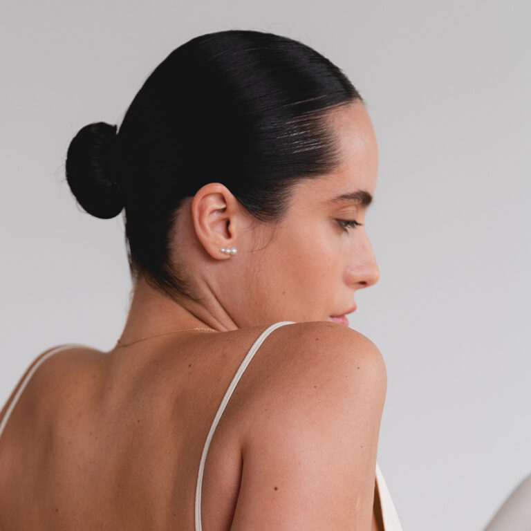 mulher usando Brinco minimalista feito a mão em ouro 18k com três pérolas naturais em tamanhos diferentes