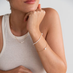 Mulher usando colar e pulseira feita a mão em ouro 18k com pérolas brancas naturais de tamanhos diferentes