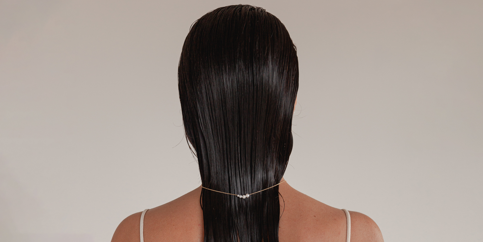 mulher de cabelo molhado usando colar minimalista feito à mão em ouro 18k com quatro pérolas brancas naturais