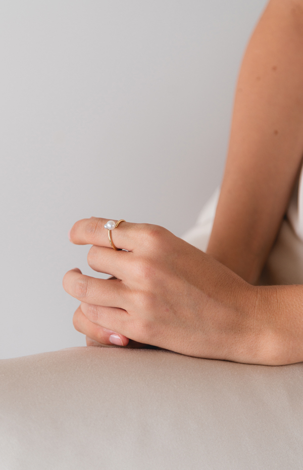 mulher usando anel feito à mão em ouro 18k com duas pérolas brancas naturais de tamanhos diferentes