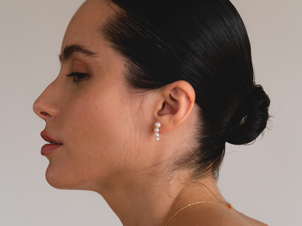 mulher usando brinco de pino minimalista feito à mão em ouro 18k com quatro pérolas brancas naturais de diferentes tamanhos