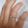 mão feminina vestindo anel de noivado em ouro 18k amarelo com turmalina paraíba natural
