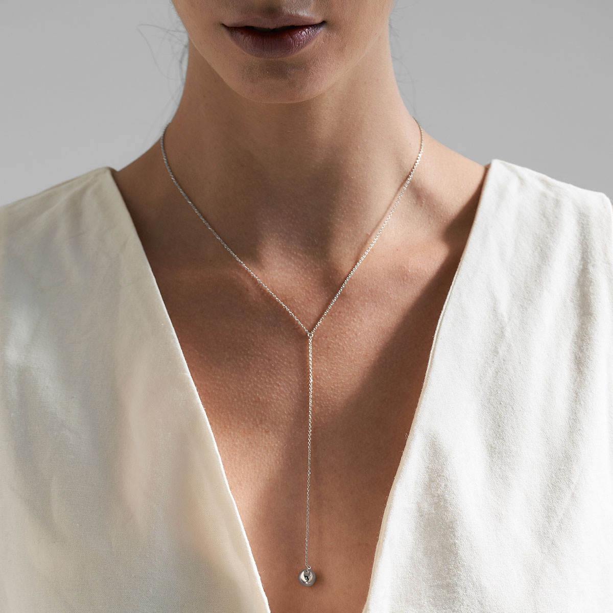 mulher usando colar feito a mão em ouro 18k de modelo gravatinha com esfera na ponta