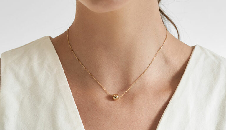 mulher usando colar minimalista feito a mão em ouro 18k com fecho magnético em formato de esfera
