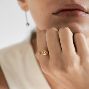 mulher usando anel minimalista feito a mão em ouro 18k com aro redondo e esfera