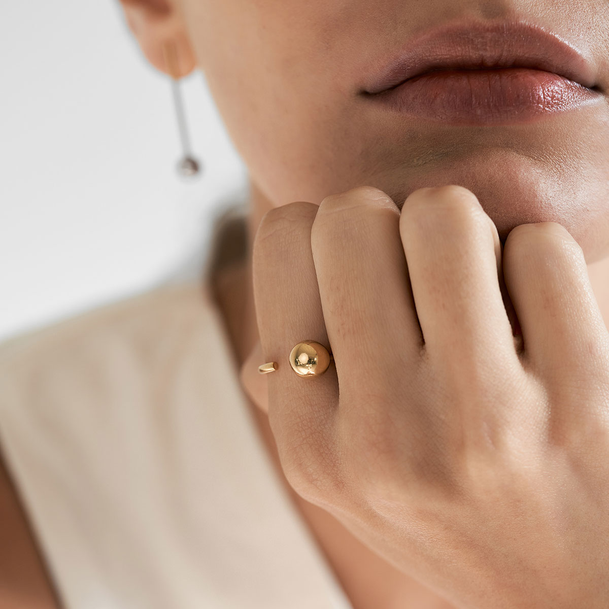 mulher usando anel minimalista feito a mão em ouro 18k com aro redondo e esfera