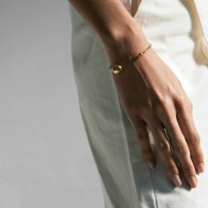 mulher usando bracelete minimalista feito a mão em ouro 18k com duas esferas na ponta do aro