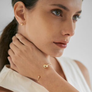 mulher usando bracelete minimalista feito a mão em ouro 18k com duas esferas na ponta do aro