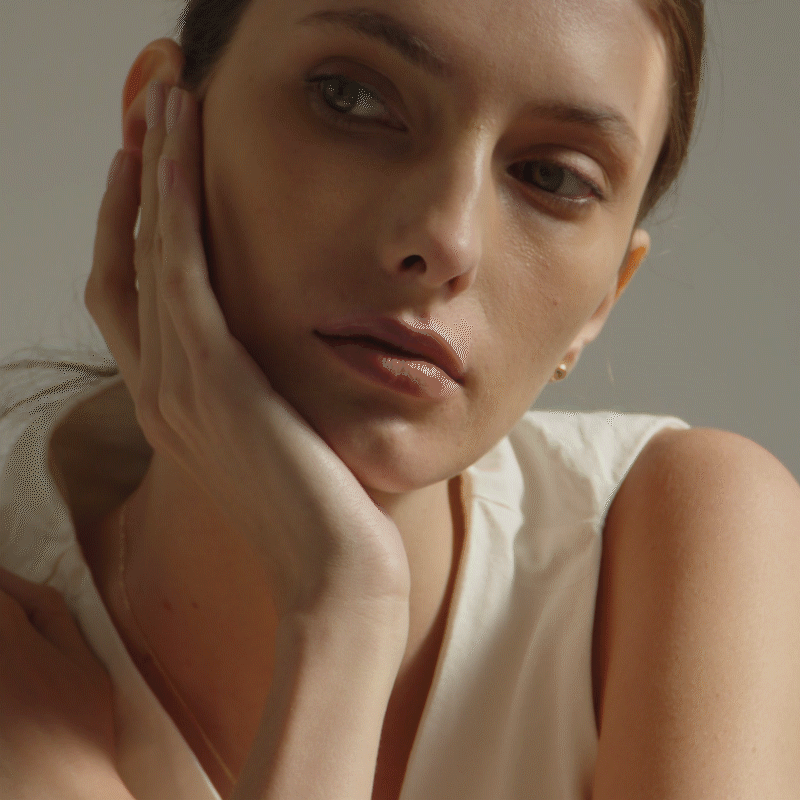 mulher de pele clara e blusa branca usando brinco minimalista feito à mão em forma de meia esfera em ouro amarelo 18k