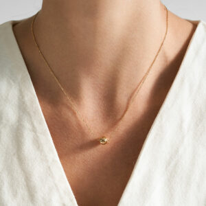 mulher usando colar minimalista feito a mão em ouro 18k com fecho magnético em formato de esfera