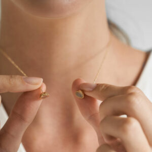 mulher usando colar minimalista feito a mão em ouro 18k com fecho magnético em formato de esfera