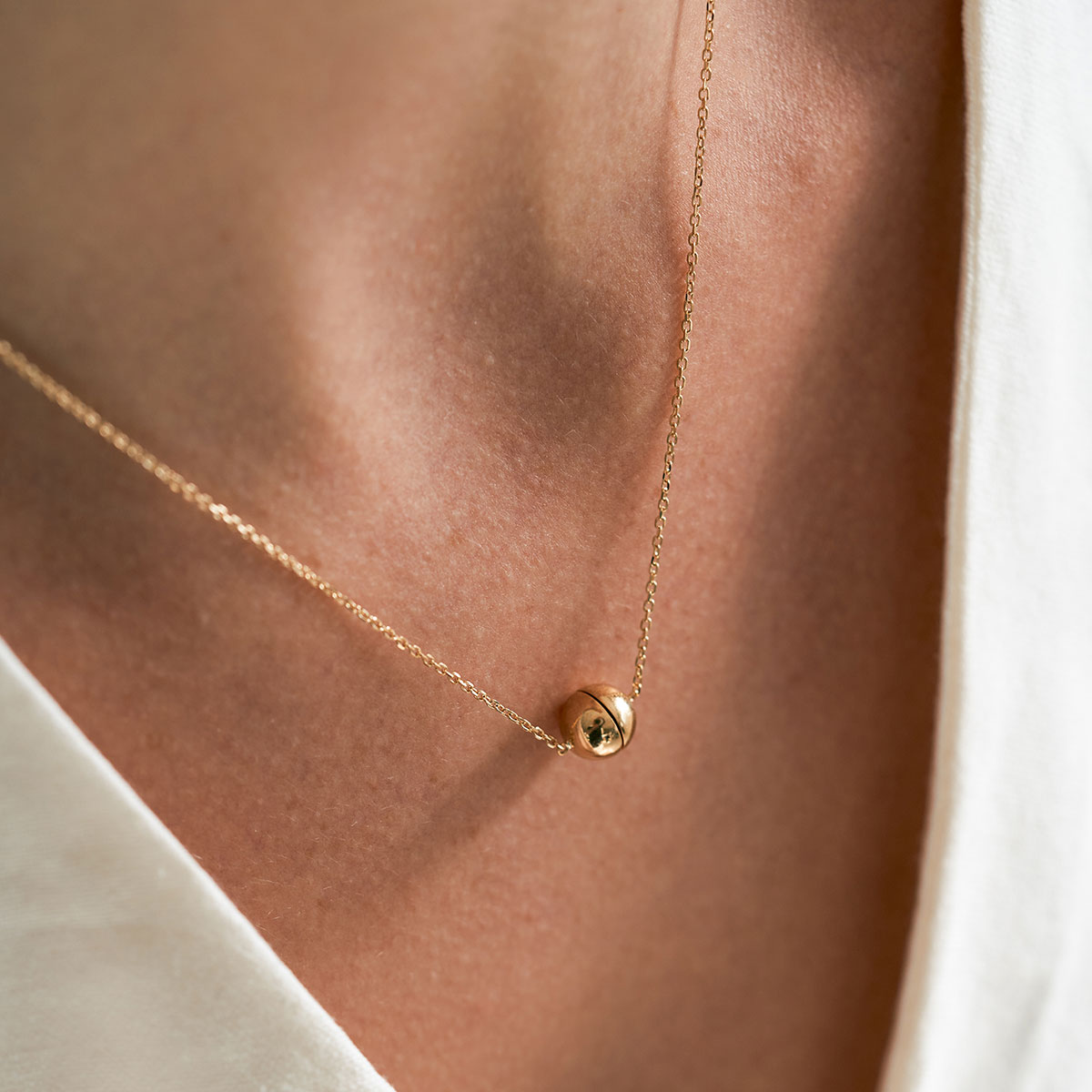 mulher usando colar minimalista feito a mão em ouro 18k com fecho magnético em formato de esfera