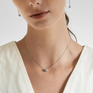 mulher usando colar minimalista feito a mão em ouro 18k com fecho magnético em formato de esfera