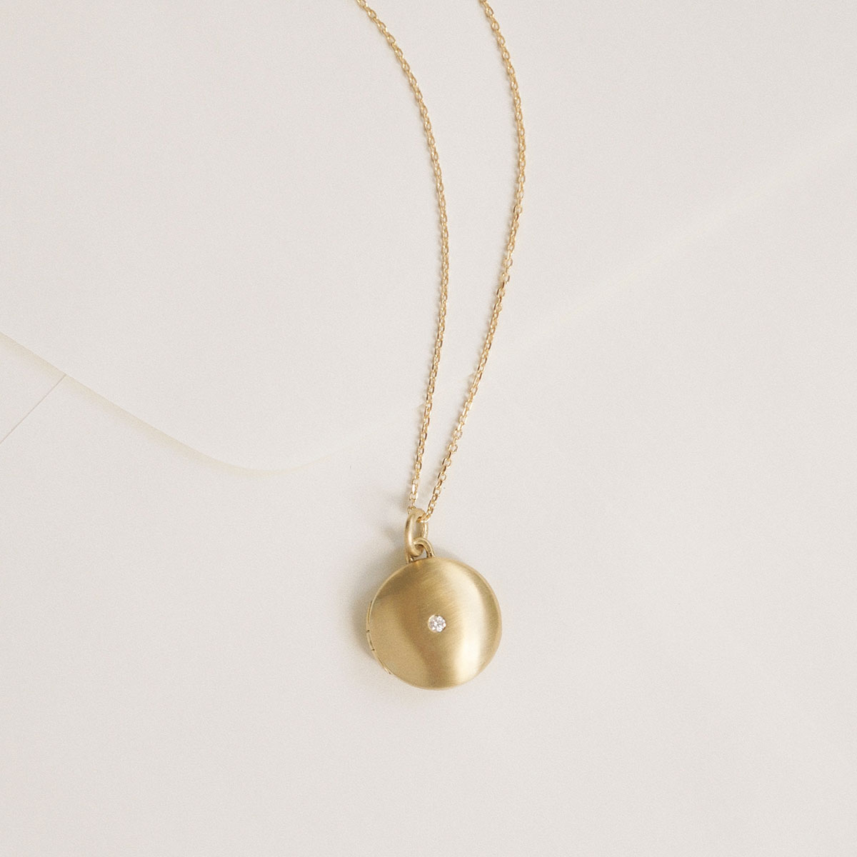 relicário minimalista de ouro com diamante, com espaço para duas fotos