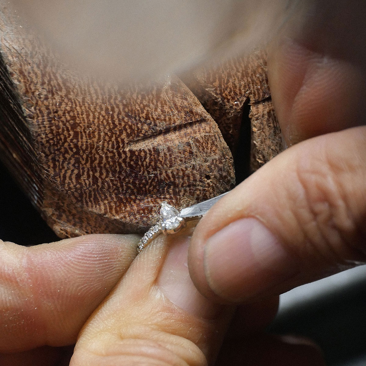 Anel de noivado sendo feito à mão por ourives em ouro 18k com aro cravejado de diamantes e no centro um diamante em formato de gota