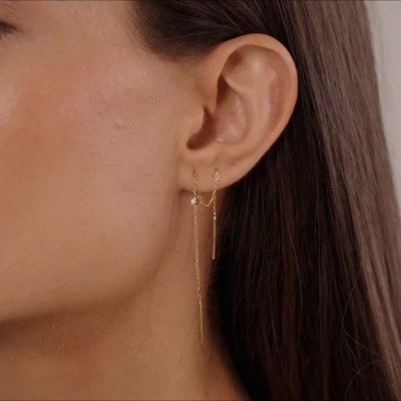 vídeo de mulher usando brinco minimalista feito à mão em ouro 18k de corrente e diamante que passa pelos dois furos da orelha