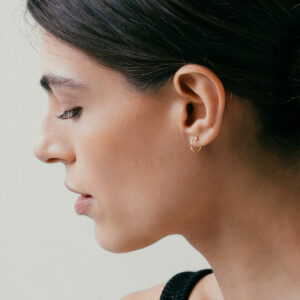mulher usando brinco de argola minimalista fino com um diamante feito à mão em ouro 18k