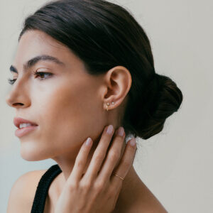mulher usando brinco de argola minimalista fino com um diamante feito à mão em ouro 18k