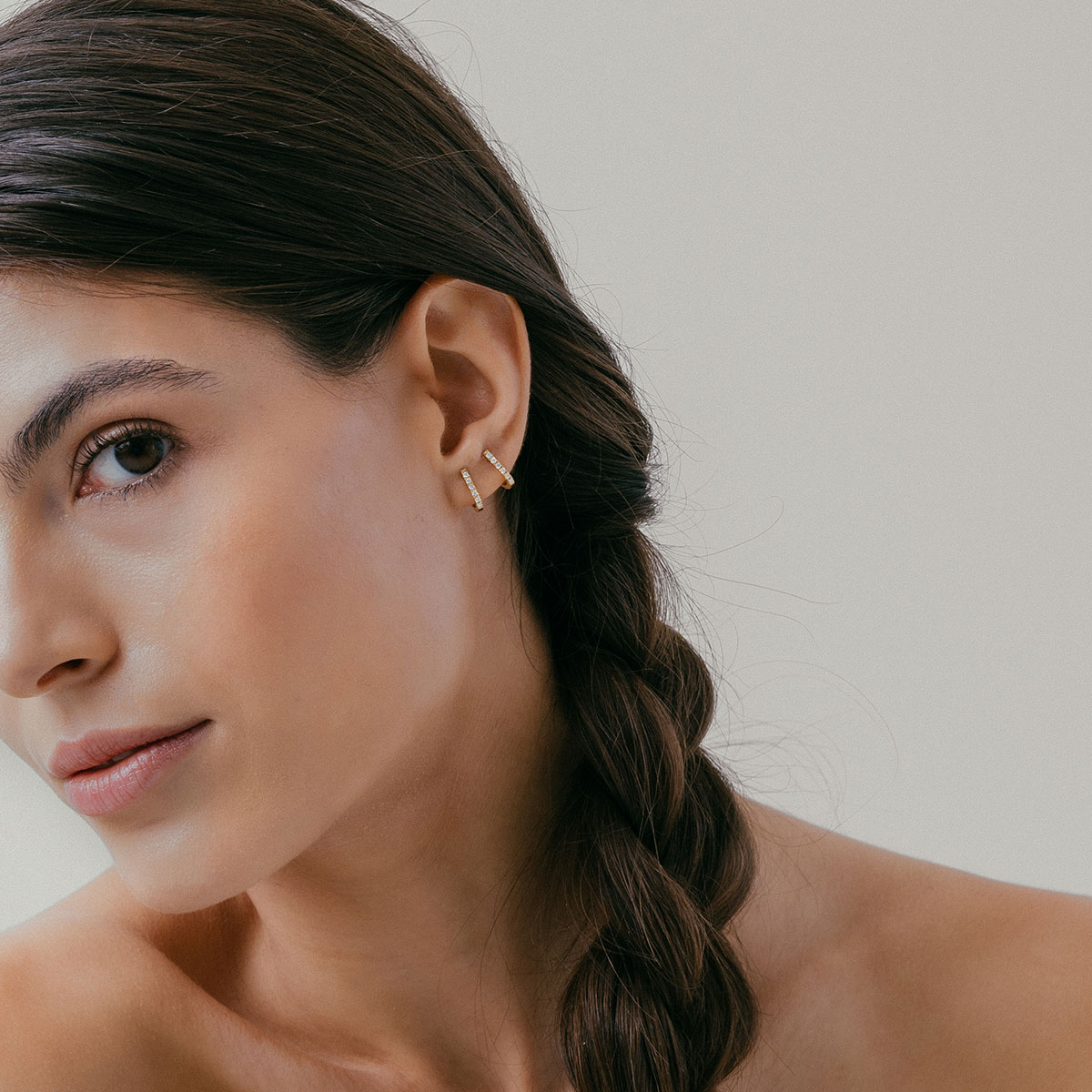 mulher usando brinco minimalista feito à mão em ouro 18k com diamantes que abraça a orelha de forma delicada e sutil