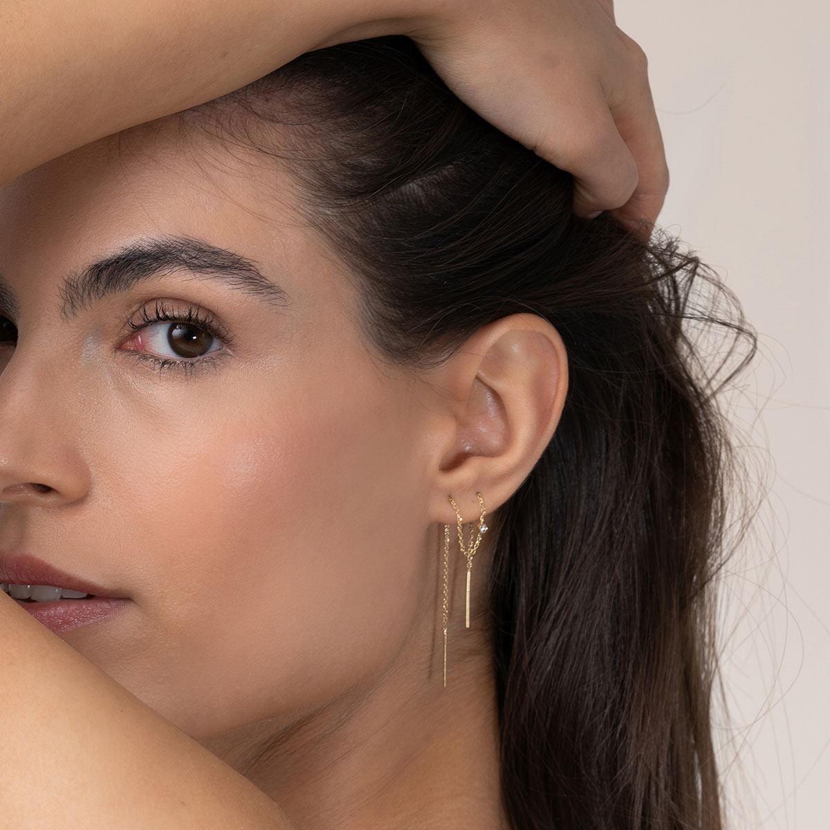 mulher usando brinco longo minimalista de corrente maleável feito à mão em ouro 18k com um diamante delicado